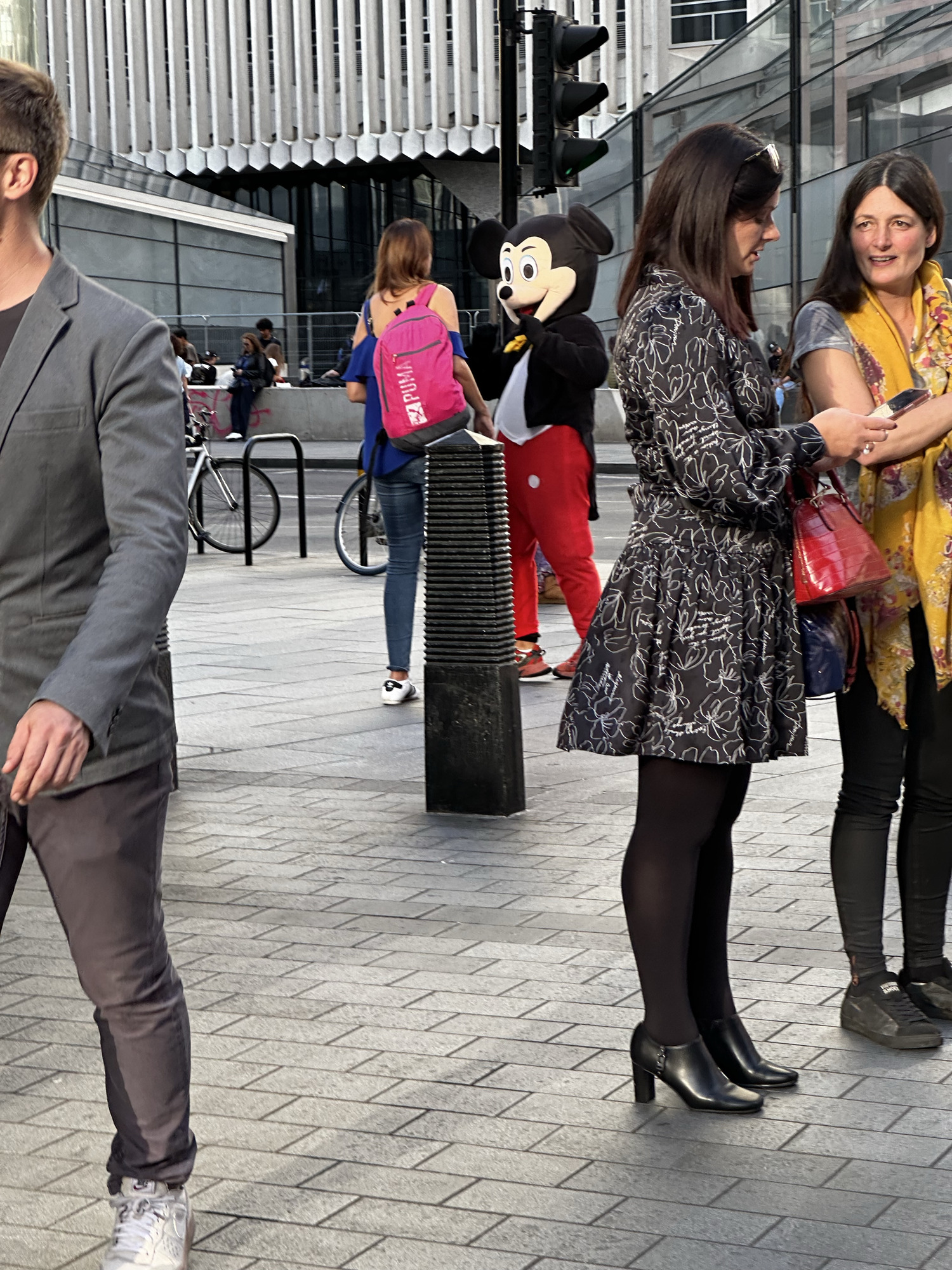 Person in a Mickey Mouse costume among pedestrians on a paved city square
