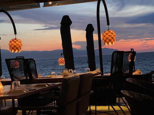 Restaurant terrace with hanging lamps overlooking the sea at sunset