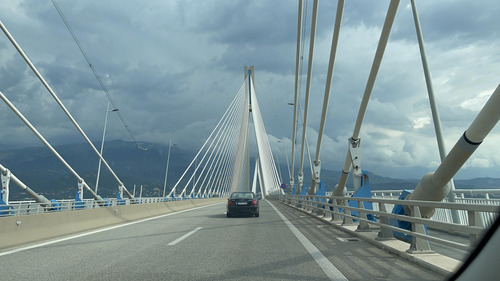 Car crossing a long cable-stayed bridge under cloudy skies