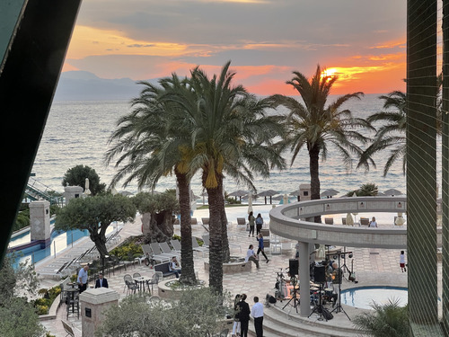 Seaside resort terrace with palm trees and a pool at sunset