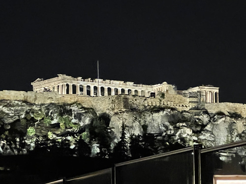 Ancient columned ruins lit up on a rocky hilltop at night