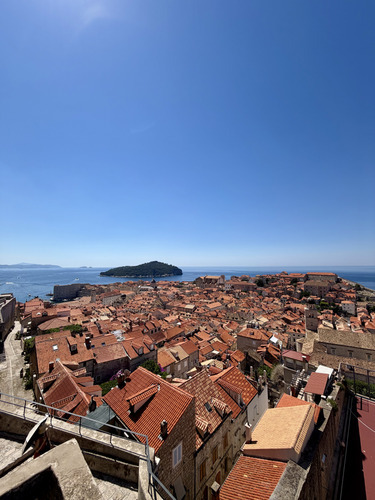 Red-tiled rooftops of an old town by the sea with an island offshore