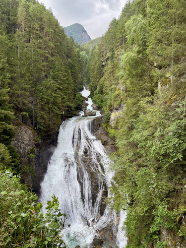 Waterfall rushing through a forested mountain valley