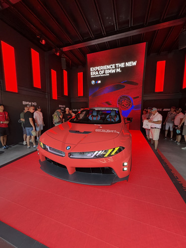Red BMW M concept car on a red stage under a display screen