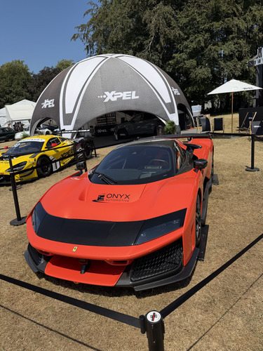 Orange Ferrari supercar on grass in front of a dome tent