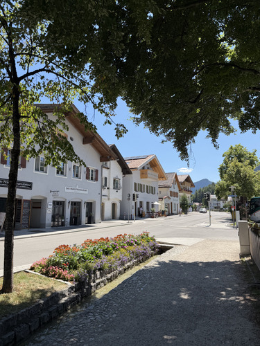 Sunny street of white houses with a flower bed and mountains in the distance
